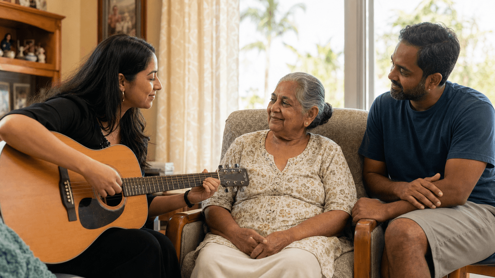 Music therapist playing guitar with a hospice patient and family caregiver