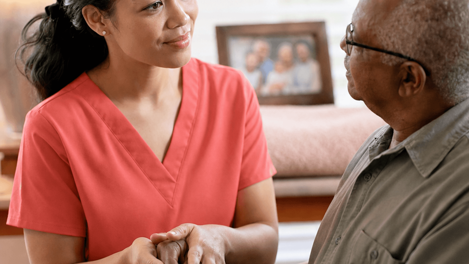 Hospice massage therapist in plain coral scrubs providing personalized comfort touch