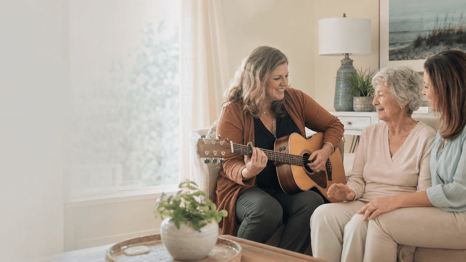 Music therapist playing acoustic guitar for a hospice patient and family member